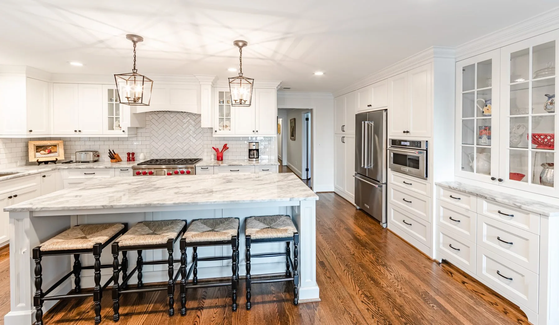 Custom espresso kitchen cabinetry with a white marble waterfall island, built by Distinctive Cabinets